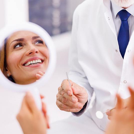 Dental patient’s face reflected in hand mirror