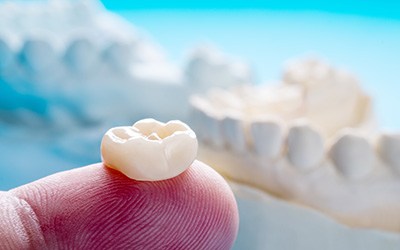 Dental crown resting on person’s fingertip